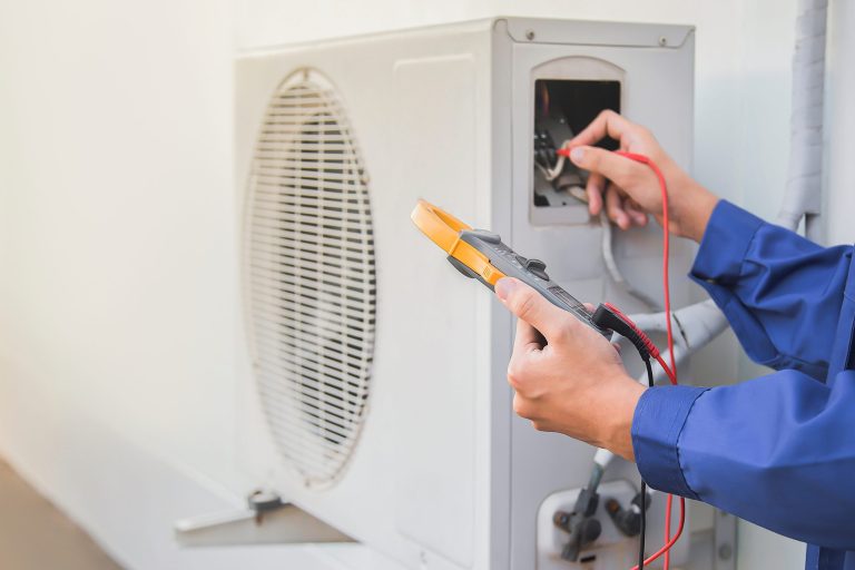 HVAC technician testing an outdoor AC unit