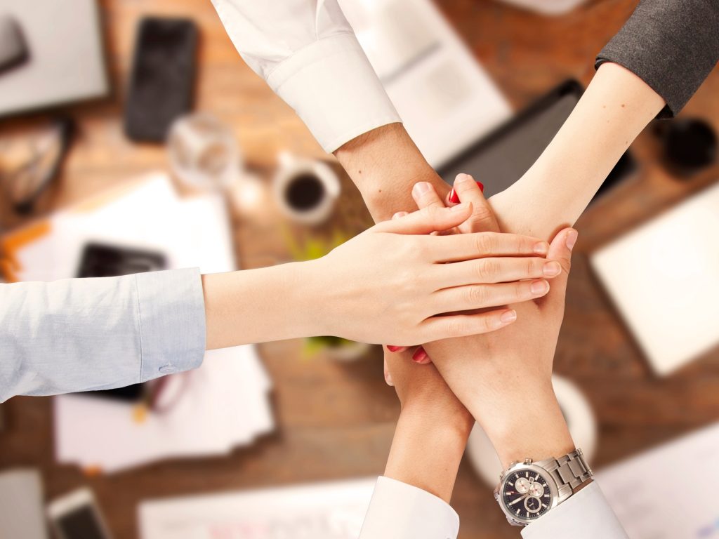 Hands of a team coming together over a desk